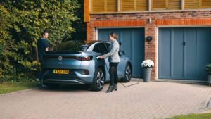 An electric car charging at a home while couple is talking to each other. 